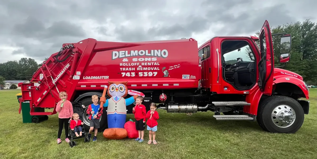 Children beside a red Delmolino & Sons truck at an outdoor event
