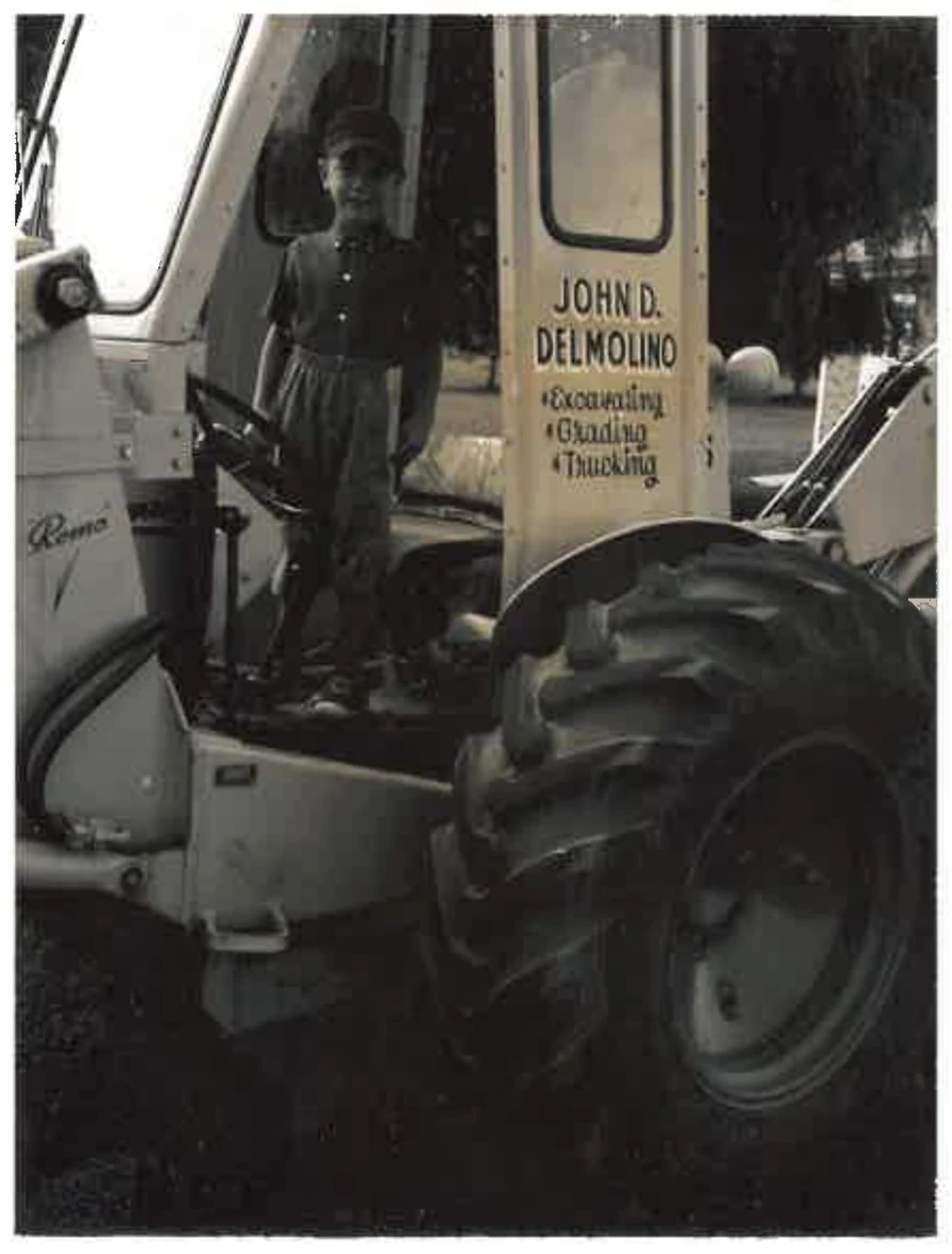 Historic equipment bearing the John D. Delmolino name, with a person at the controls