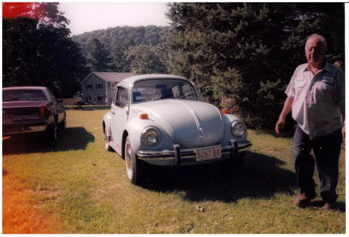 John Delmolino standing beside a Volkswagen Beetle