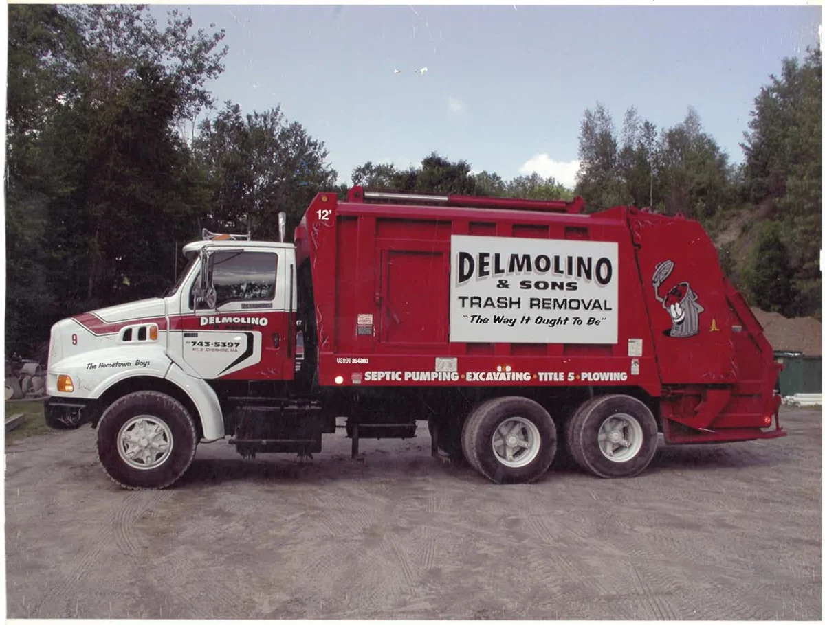 Red and white Delmolino and Sons trash collection truck with the company name and mascot on the side
