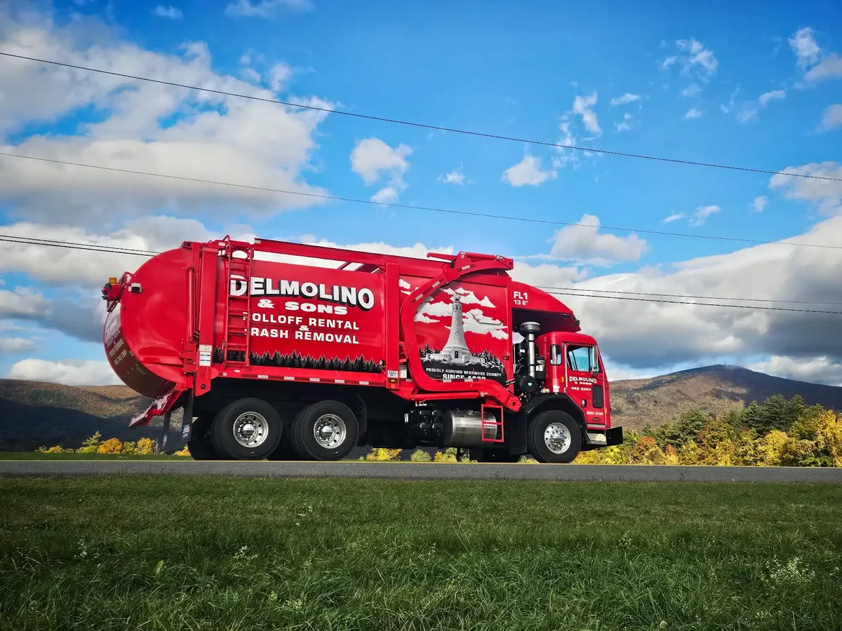 Red Delmolino & Sons trash collection truck with Berkshire hills in the background